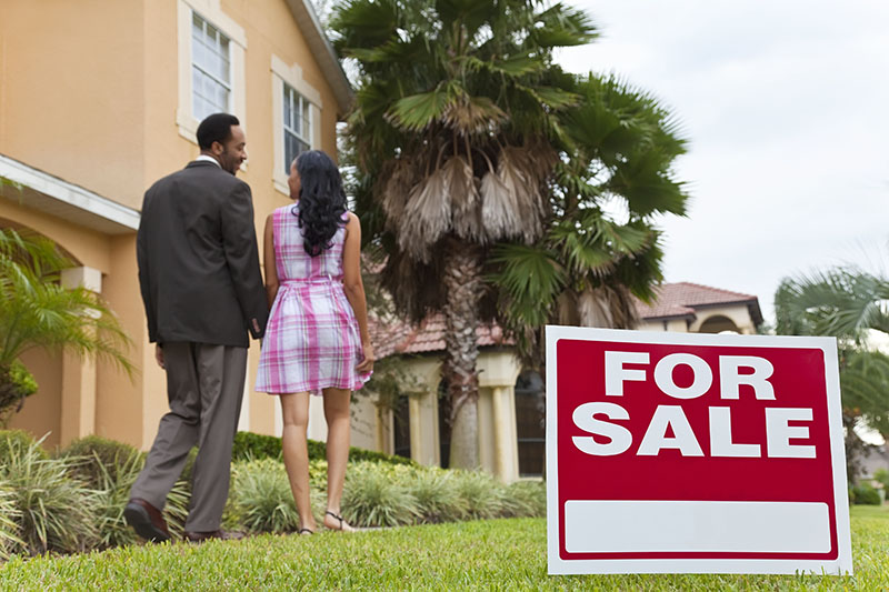 For sale sign in front of a house seen before scheduling home inspection services 